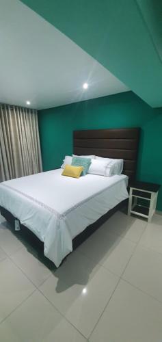 um quarto com uma cama grande e uma parede verde em TERTIUS LODGE em Nelspruit