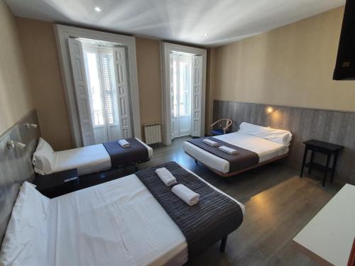 a hotel room with two beds and a table at Plaza Dort Rooms IV in Madrid