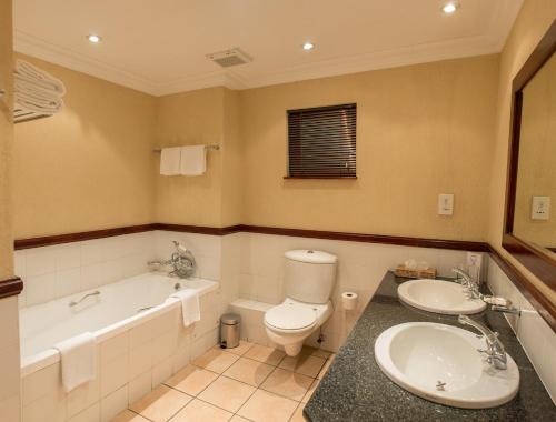 uma casa de banho com uma banheira, um WC e um lavatório. em Peermont Mondior Hotel em Gaborone