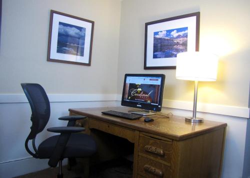a desk with a computer on it with a lamp and a chair at Cardinal Hotel in Palo Alto