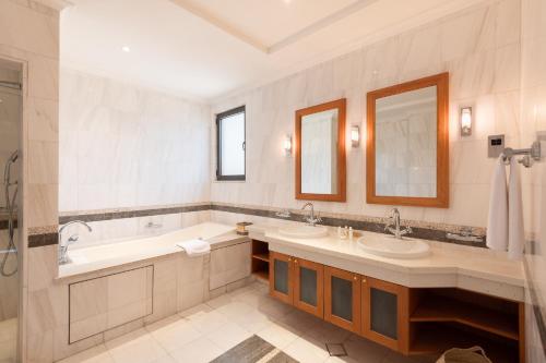 a bathroom with two sinks and a tub and mirrors at Maison Privee - Prvt Pool & Beach! in Luxury Palm Jumeirah Villa in Dubai