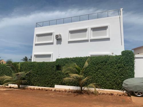a white house with a hedge in front of it at Appartement Luxueux En Résidence vu sur mer à 50 mètres de la plage in Sali Tapé