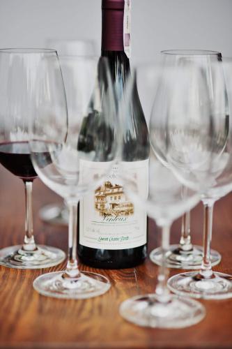 a bottle of wine and three wine glasses on a table at Hotel Villa Bohema in Kazimierz Dolny