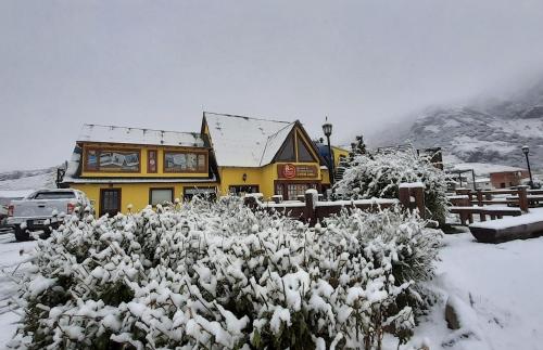 a building covered in snow with a bush in front of it at Rancho Grande Hostel in El Chalten