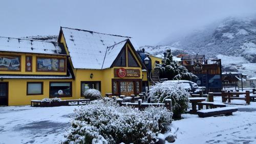 a building covered in snow with benches in front of it at Rancho Grande Hostel in El Chalten