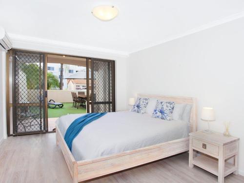 a white bedroom with a bed and a balcony at 2 bedroom Apt on Parkyn Parade with pool and Airvconditioning in Mooloolaba