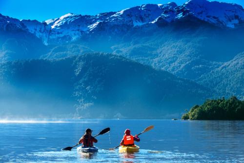two people in kayaks on a lake with mountains at Puyuhuapi Lodge & Spa in Puerto Puyuhuapi