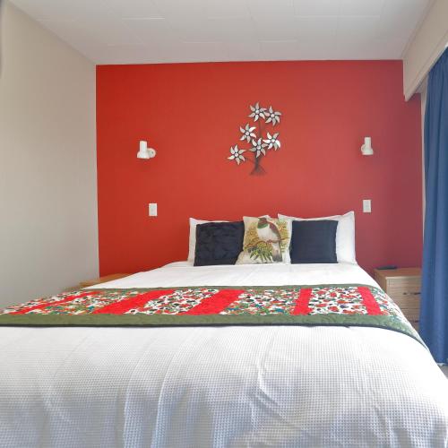 a bedroom with a bed with a red wall at Aden Motel in Te Anau