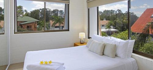 a white bed in a room with a large window at Main Beach Apartments in Byron Bay