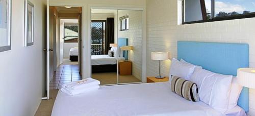 a hotel room with a bed, desk and a television at Main Beach Apartments in Byron Bay