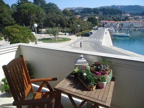 a balcony with a wooden table with flowers and a bench at M. DE DOMINISA 5 in Rab