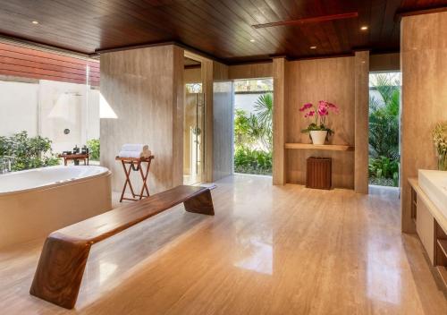 a bathroom with a tub and a wooden floor at The Edge Bali in Uluwatu