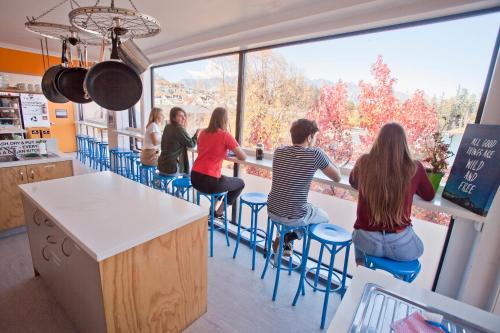 Un groupe de personnes assises à un comptoir dans une cuisine dans l'établissement Absoloot Hostel Queenstown, à Queenstown