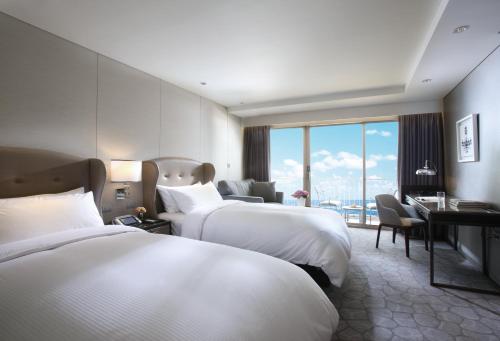 a hotel room with two beds and a desk at Paradise Hotel Busan in Busan