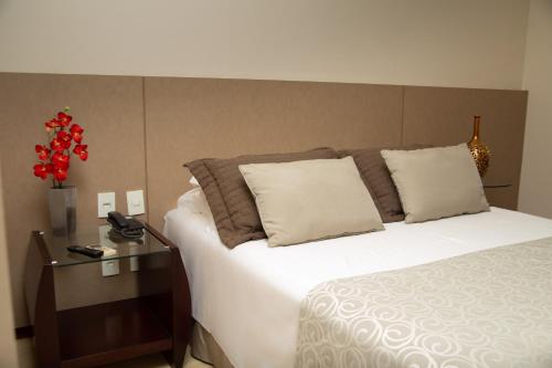 a bedroom with a bed and a vase with red flowers at Mara Turismo Hotel in Catalão