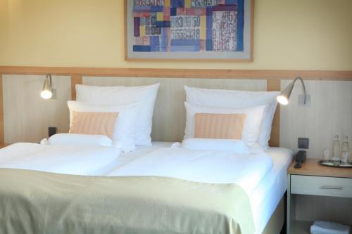 a bedroom with two beds with white sheets and pillows at Lindner Hotel Cologne Am Dom, part of JdV by Hyatt in Cologne