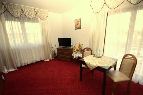a living room with a table and a television at Pensjonat Korona in Modrzyca