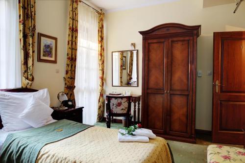 a bedroom with a bed and a wooden cabinet at Hotel Villa Bohema in Kazimierz Dolny