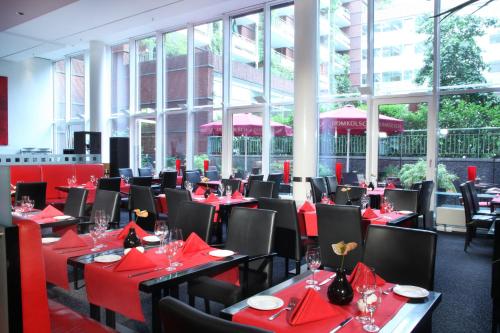 a dining room with red tables and black chairs at Lindner Hotel Cologne Am Dom, part of JdV by Hyatt in Cologne