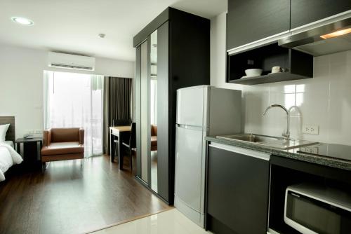 a kitchen with a sink and a refrigerator at Winner Sriracha Serviced Apartment in Si Racha
