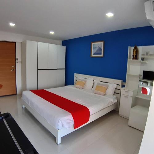 a bedroom with a large bed with a blue wall at SLT Apartment Bangkok in Bangkok