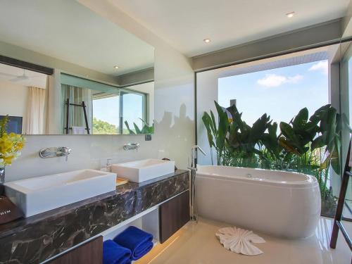 a bathroom with two sinks and a large mirror at Villa Saan - SHA Extra Plus in Kamala Beach