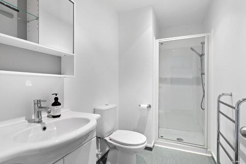a white bathroom with a toilet and a shower at TrinketBox in Wellington