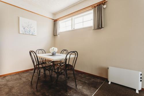 mesa y sillas en una habitación con ventana en Coromandel Cottages en Coromandel Town