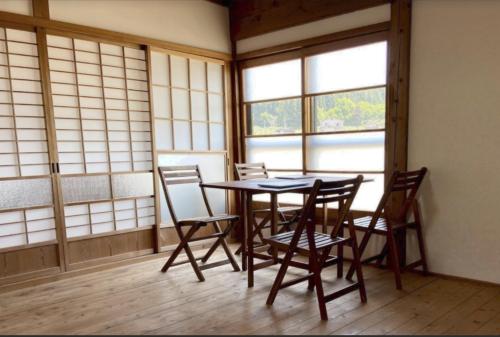 einen Tisch und Stühle in einem Zimmer mit Fenstern in der Unterkunft KOME HOME in Tōkamachi