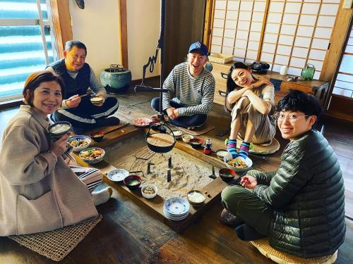 a group of people sitting around a table eating food at KOME HOME in Tokamachi