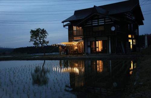 a house with a reflection in a body of water at KOME HOME in Tokamachi