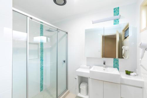 Baño blanco con ducha de cristal y lavabo en BIG4 Adventure Whitsunday Resort en Airlie Beach