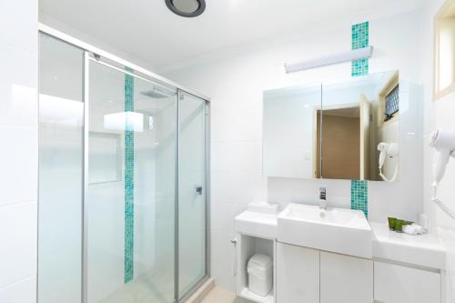 a bathroom with a shower, sink, and toilet at BIG4 Adventure Whitsunday Resort in Airlie Beach