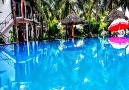 a large blue swimming pool with two umbrellas next to a building at Crescent Sea Resort in Nilaveli