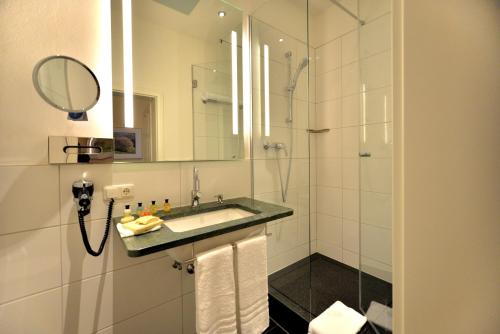 a bathroom with a sink and a shower with a mirror at Hotel Villa Ponte Wisera in Eschwege