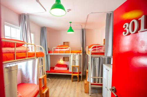 a dorm room with bunk beds and a red door at SUM Guesthouse Jeju Airport in Jeju