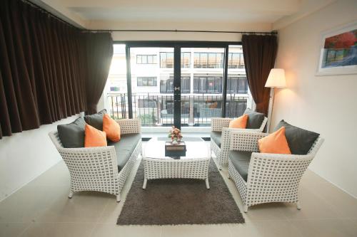 a living room with wicker chairs and a table at Summer Tree Hotel in Bangna