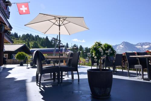 a table and chairs with an umbrella on a patio at Hotel Bettmerhof in Bettmeralp