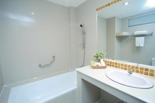 a bathroom with a sink and a tub and a mirror at Summer Tree Hotel in Bangna