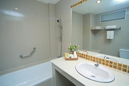 a bathroom with a sink and a tub and a mirror at Summer Tree Hotel in Bangna