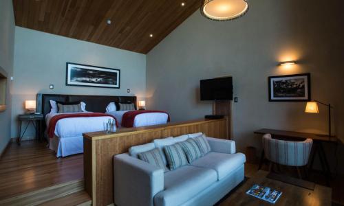 a hotel room with two beds and a couch and a tv at Uman Lodge Patagonia Chile in Futaleufú