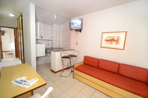 a living room with a red couch and a kitchen at Solar Flat Hotel in Juiz de Fora