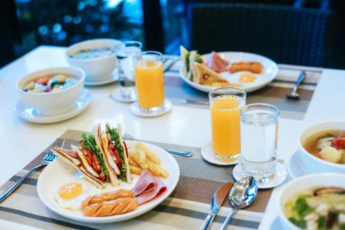 a table with plates of food and glasses of orange juice at Summer Tree Hotel in Bangna