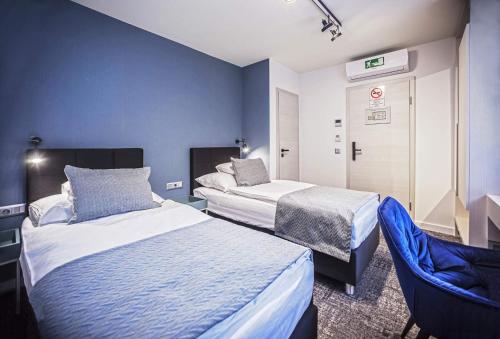 a hotel room with two beds and a chair at Piccolo Panzió Vendéglő Vinoteca in Zalaegerszeg