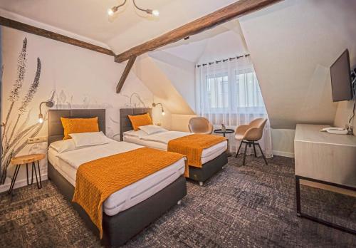 a hotel room with two beds and a television at Piccolo Panzió Vendéglő Vinoteca in Zalaegerszeg