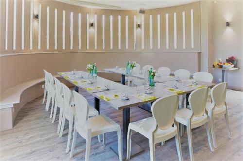 a dining room with a long table and white chairs at Logis L'Auberge de Larressingle in Larressingle