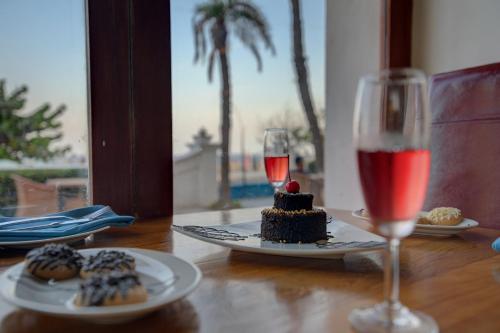 a table with a plate of cake and a glass of wine at The Promenade in Puducherry