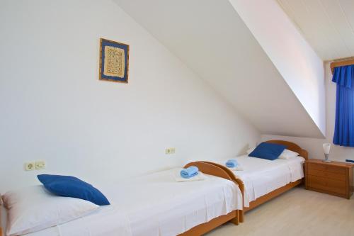 two beds in a room with white walls and blue pillows at Apartments Vinka in Jelsa