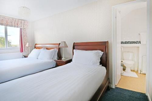 a bedroom with two beds and a bathroom with a sink at Virginia Lodge in Stratford-upon-Avon