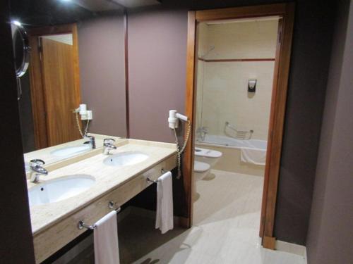 a bathroom with a sink, toilet and mirror at Hotel Alkalat in Alcalá de Guadaira